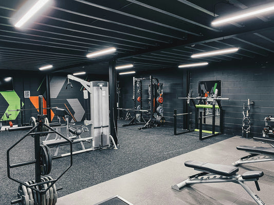Premium home gym – complete opstelling met krachtstation, halters, vloer en cardioapparaat.